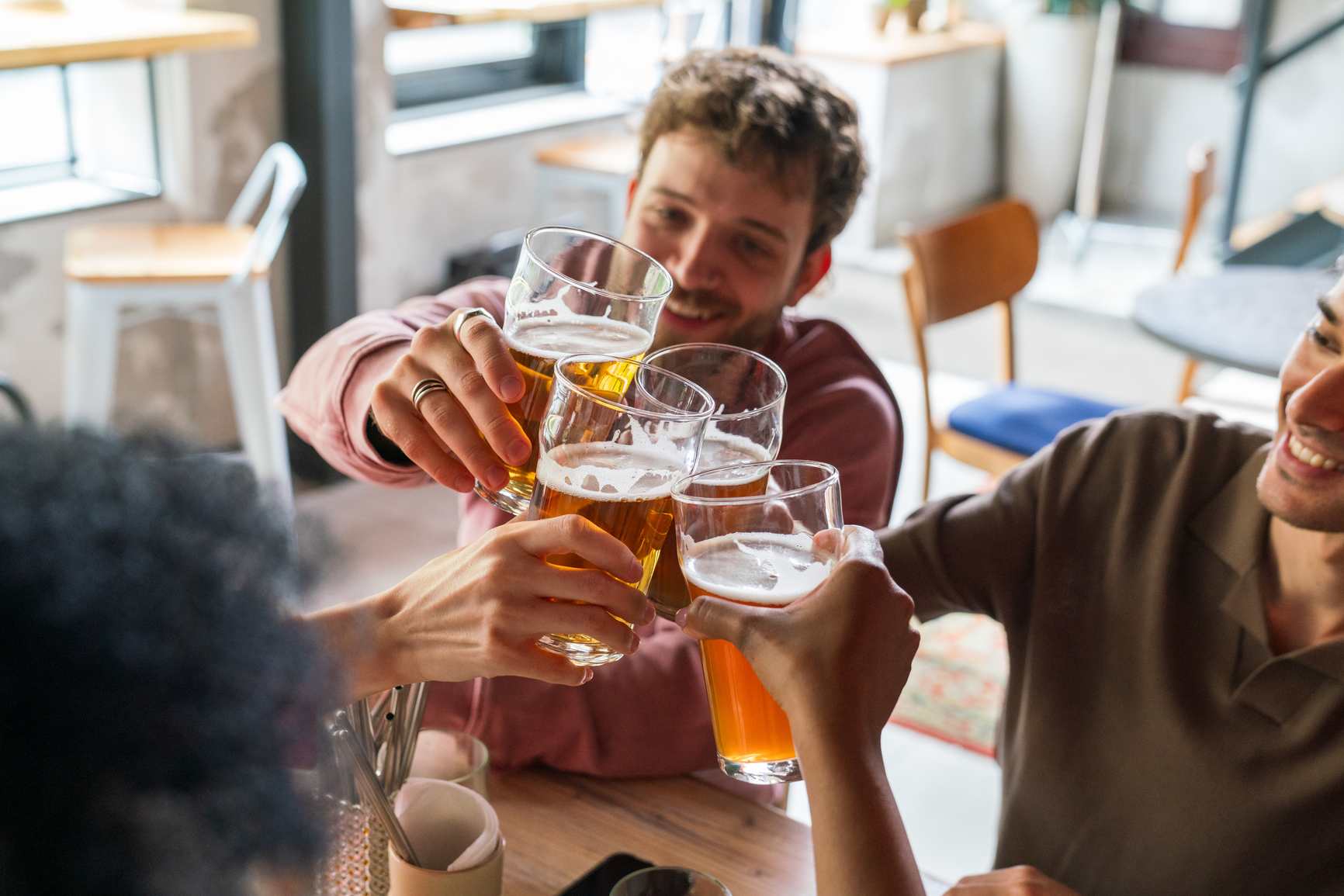 Smiling group of friends drinking alcohol at a restaurant.